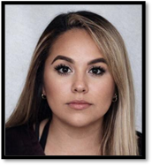 A woman with dark, highlighted hair, standing in front of a gray background.